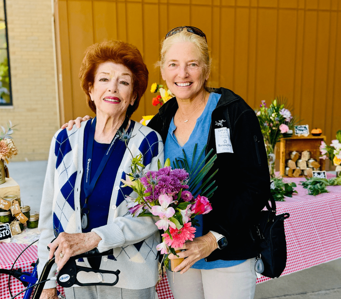 Residents posing with flowers at an outdoor event
