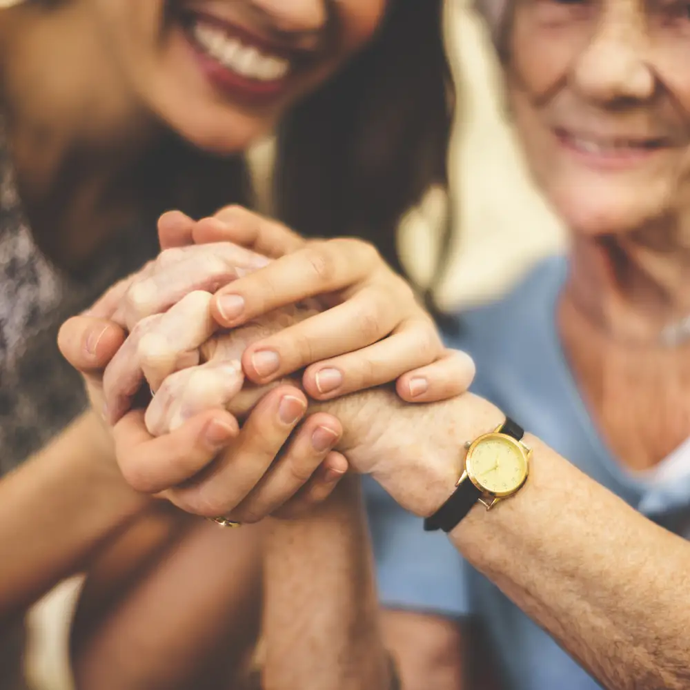 Hands of a caregiver and resident clasped together