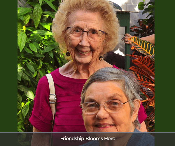 Two smiling residents posing together in a garden