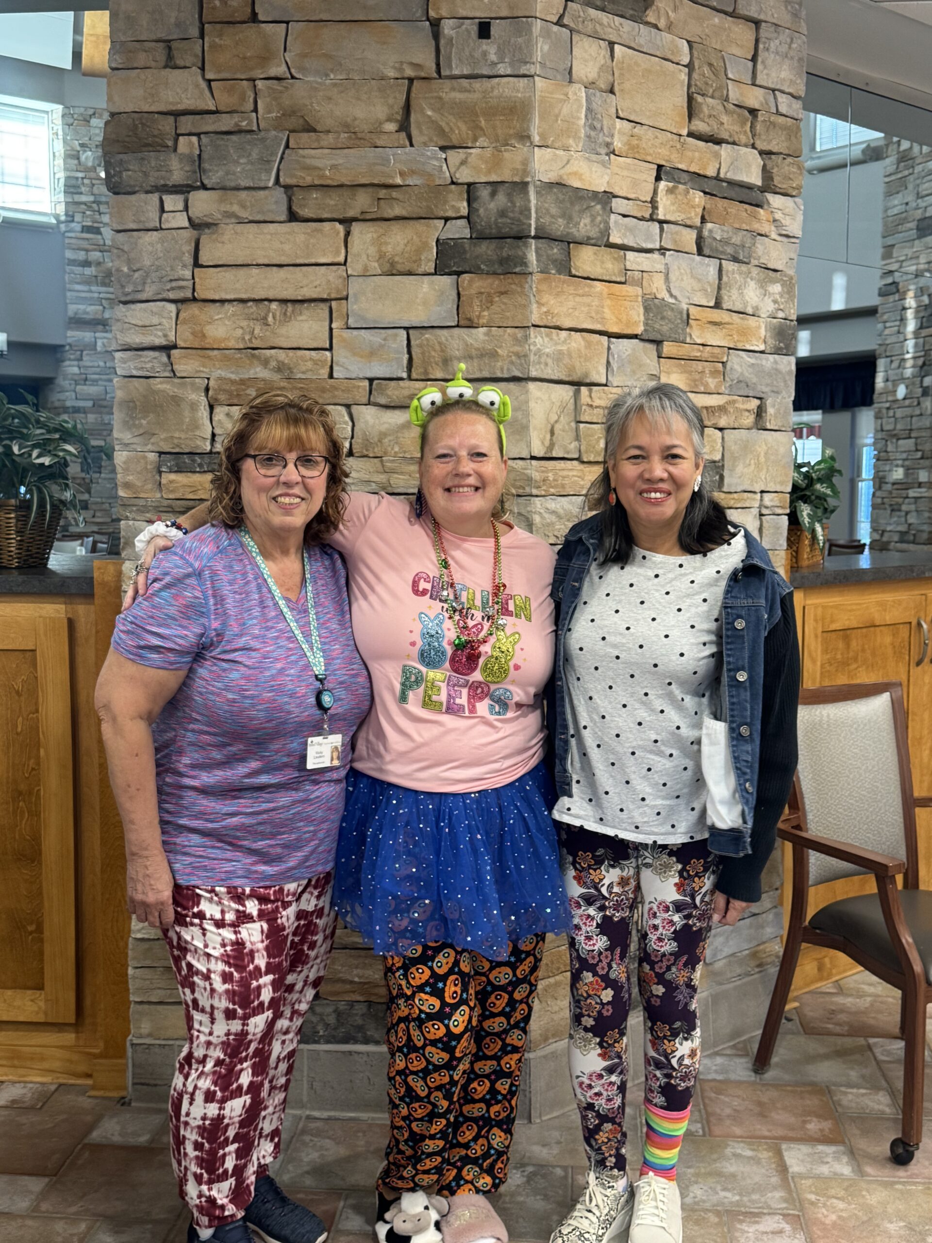Three staff members in colorful outfits in a common area