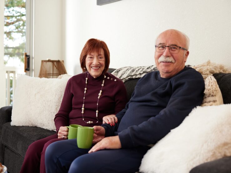 An older couple sitting together on a couch with drinks