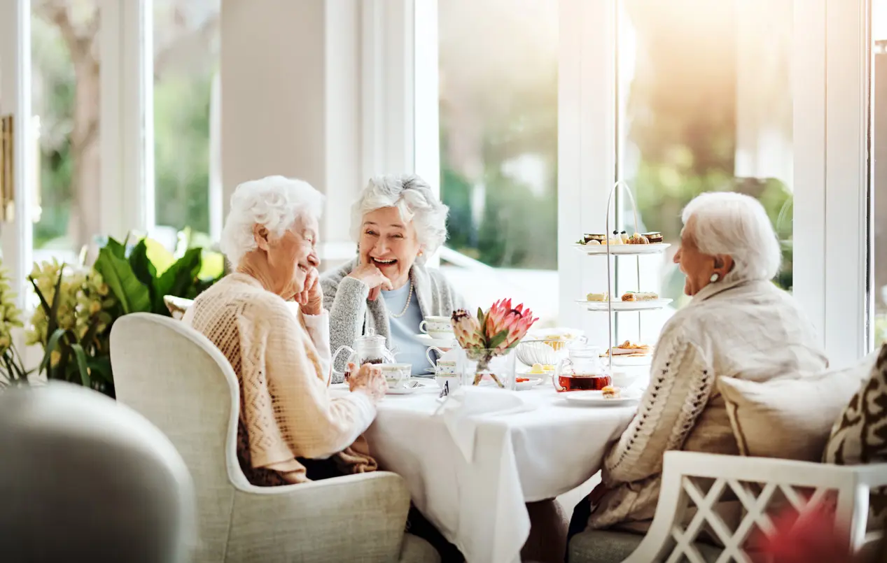 Three elderly women enjoying tea and pastries together