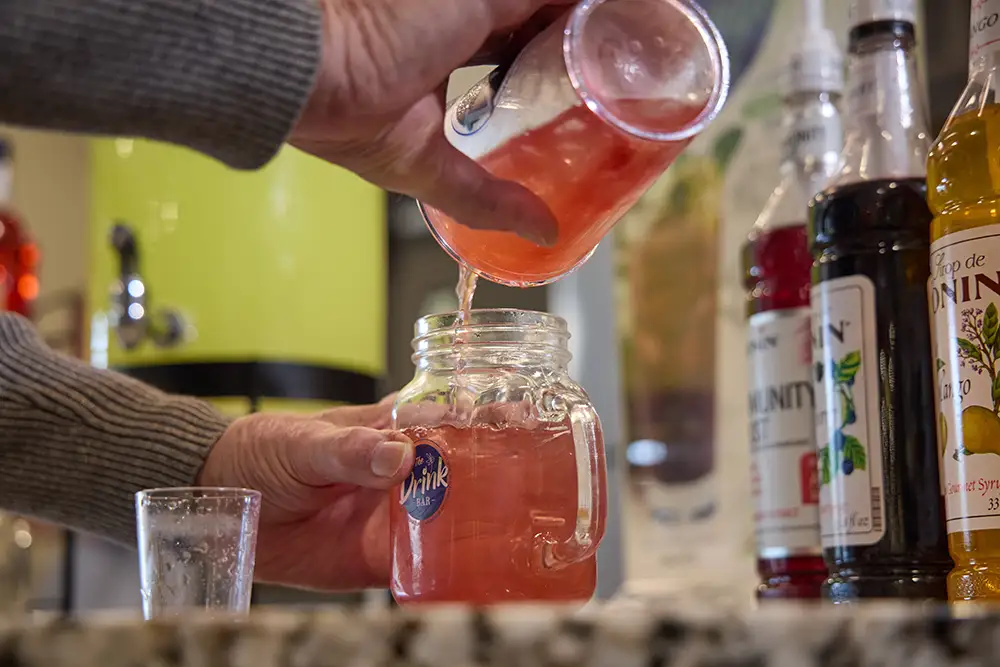 A staff member pouring a drink into a glass