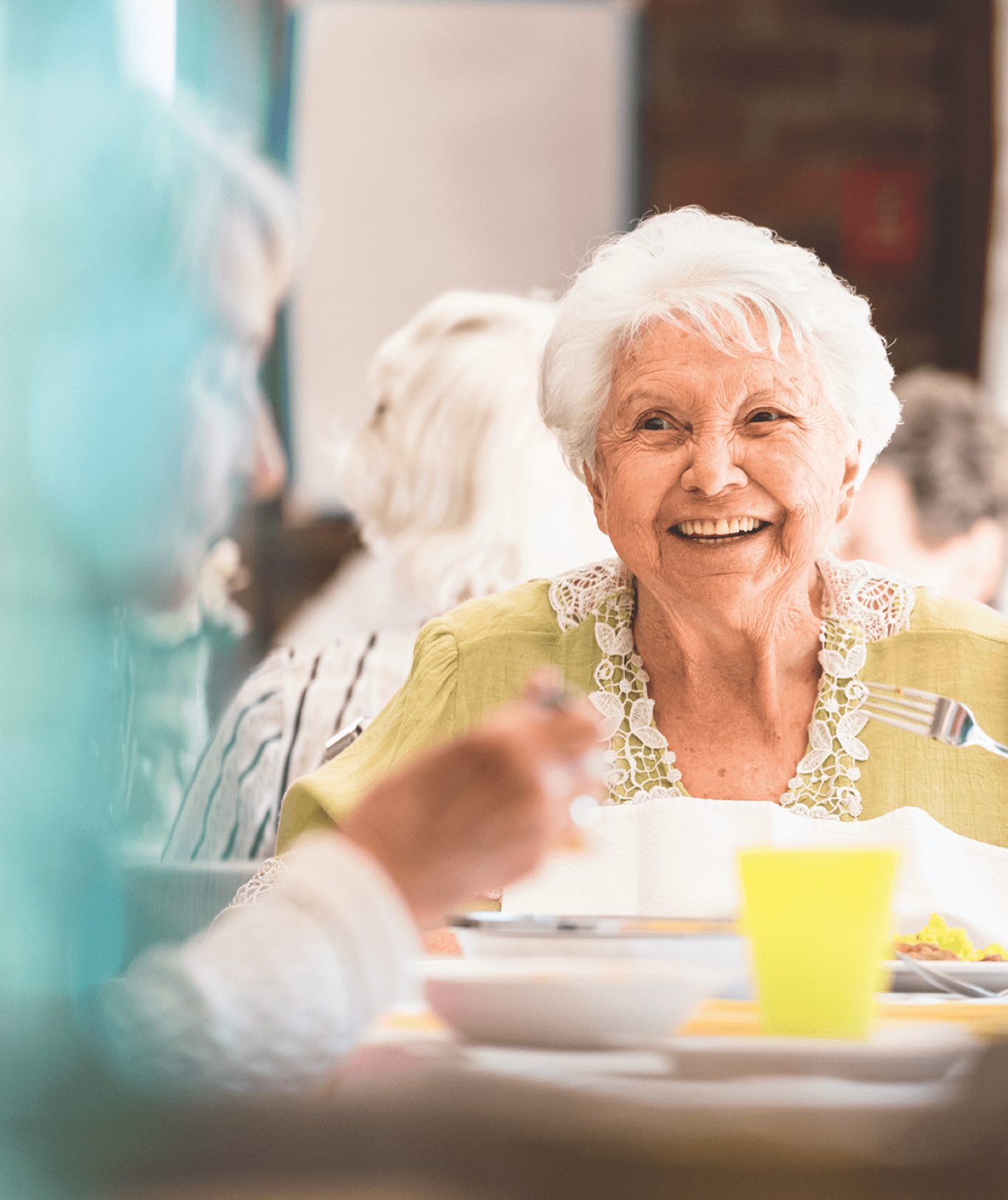 A smiling resident enjoying a meal in the dining room