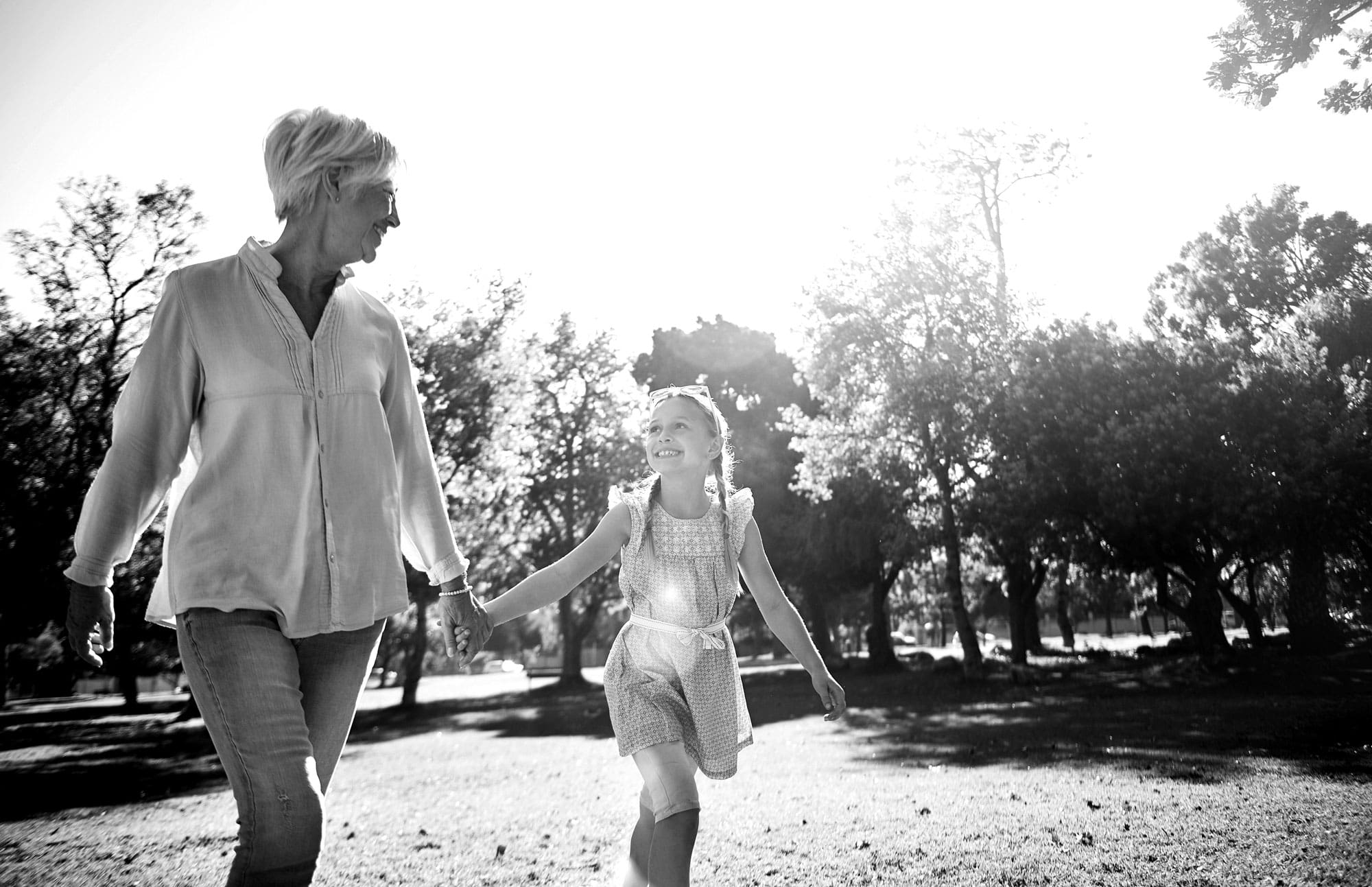 An elderly woman and a young girl walking in a park