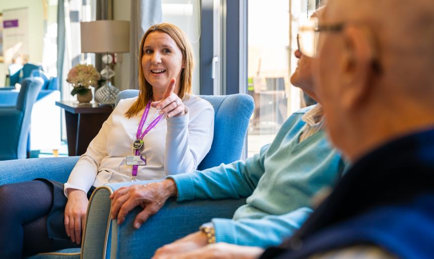 Staff member engaging with residents in a lounge setting