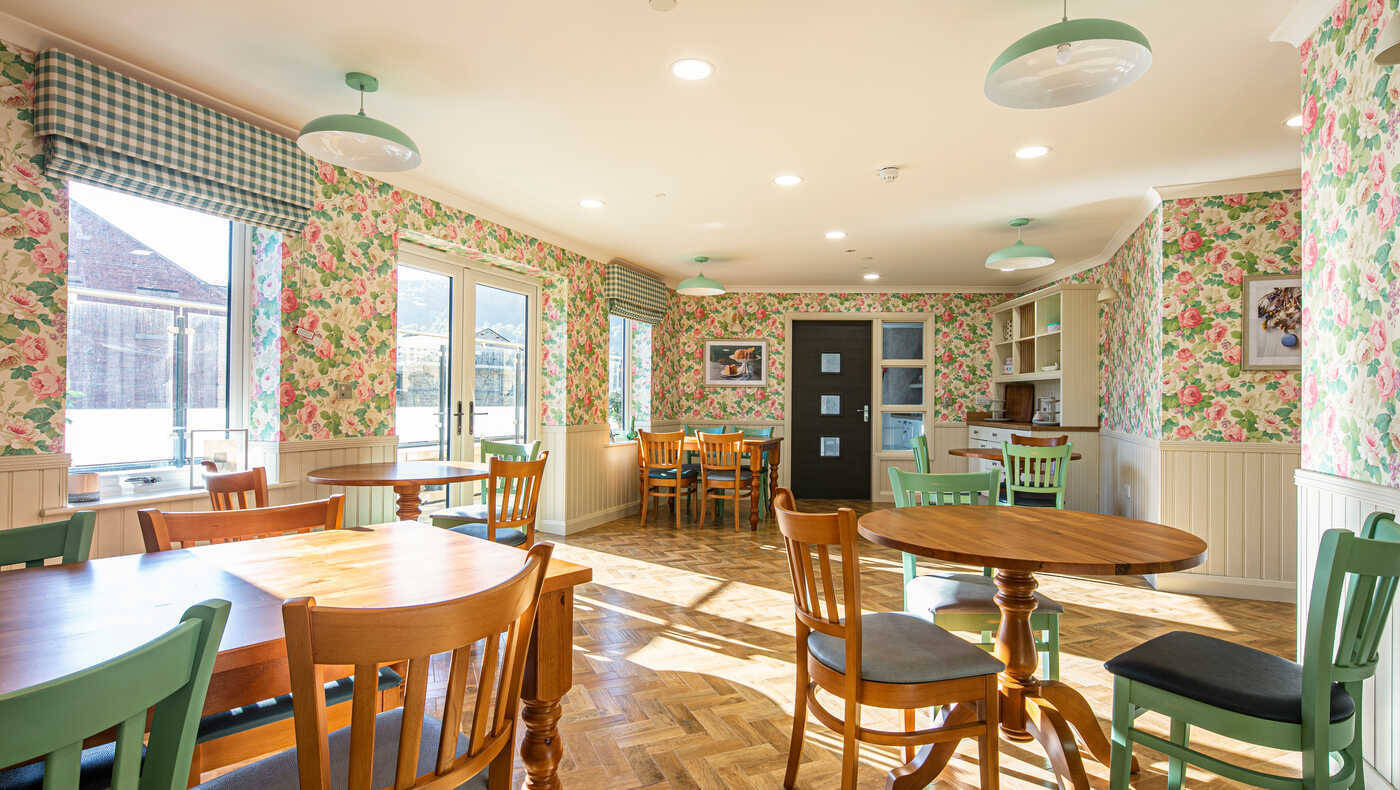 Bright dining area with floral wallpaper and wooden tables