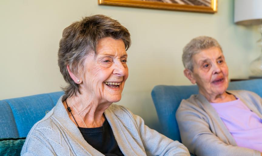 Two smiling senior women enjoying conversation indoors