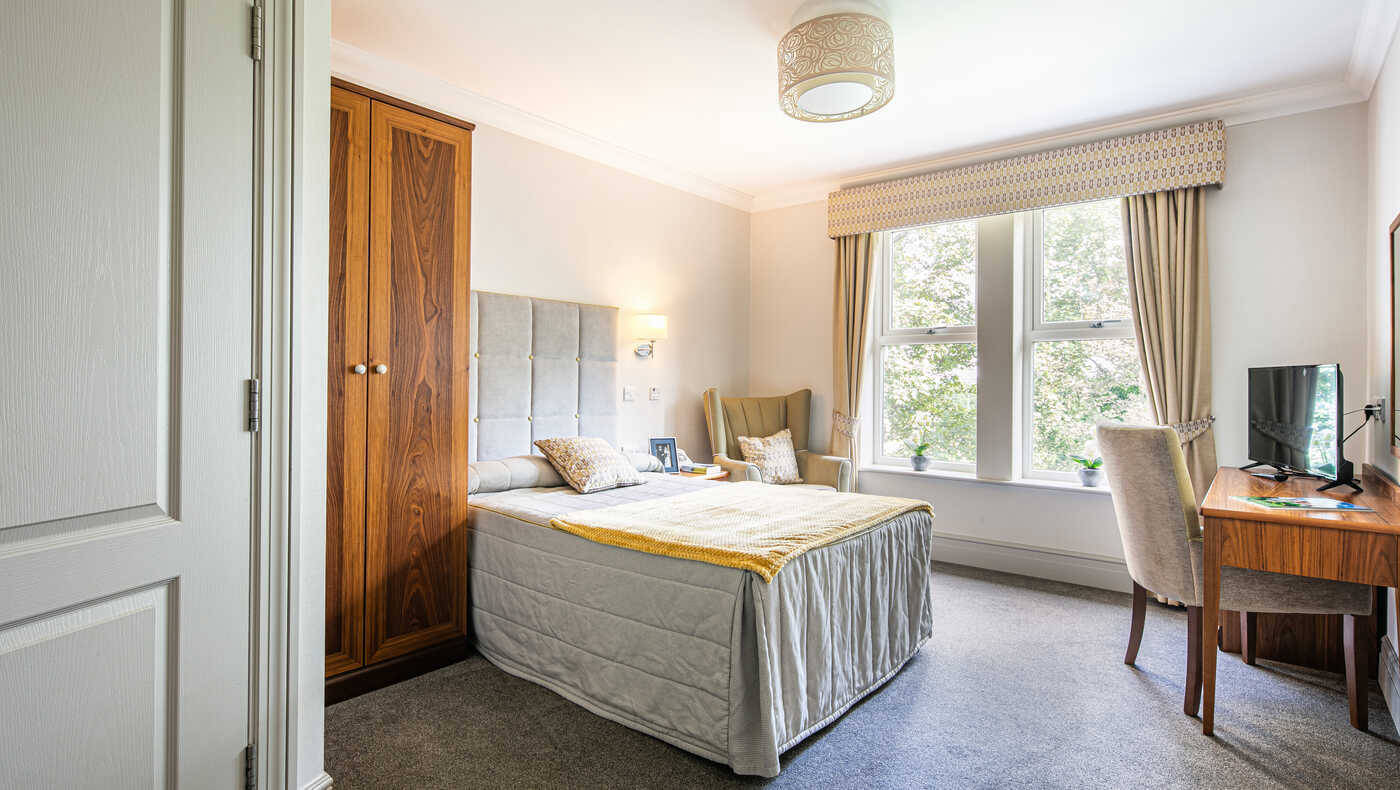 Brightly lit private room with a bed and desk