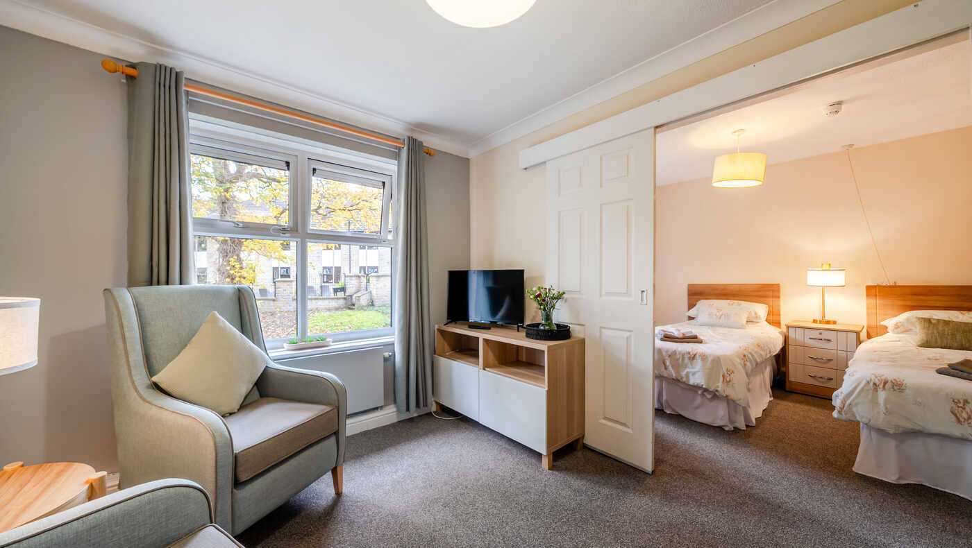 A well-furnished resident room with two beds and a TV