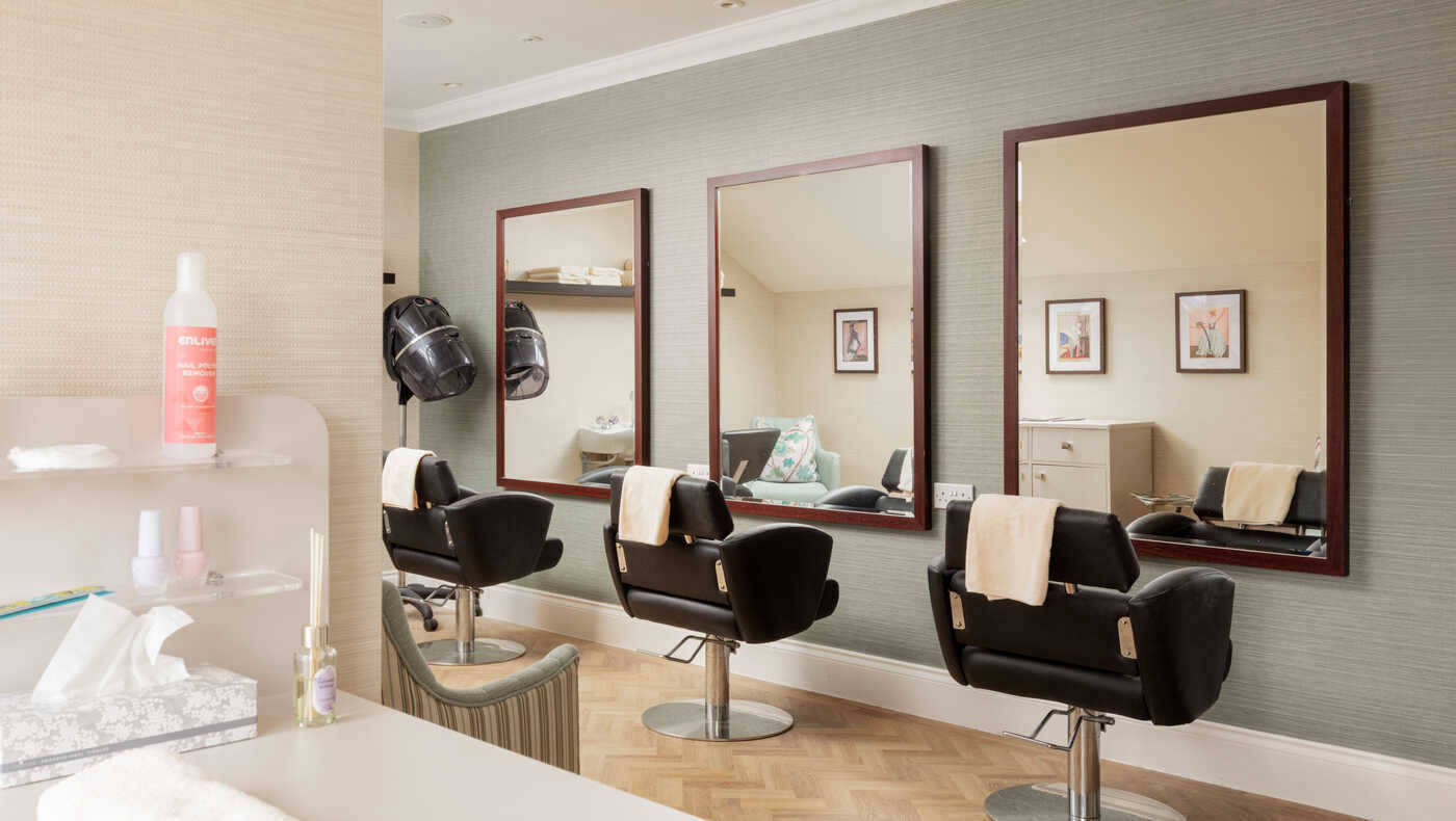 A hair salon area with three mirrors and salon chairs