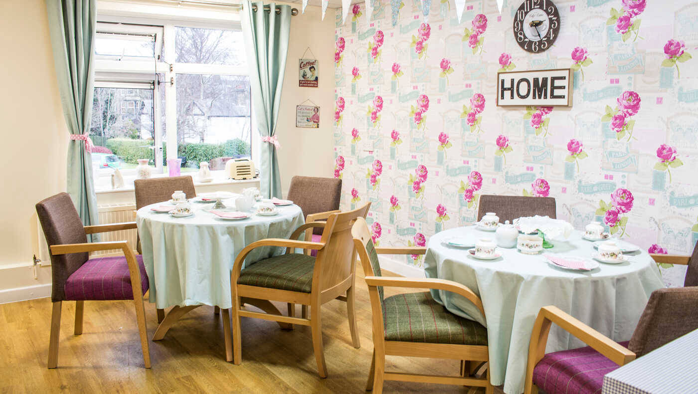 Bright dining area with flowered wallpaper and set tables