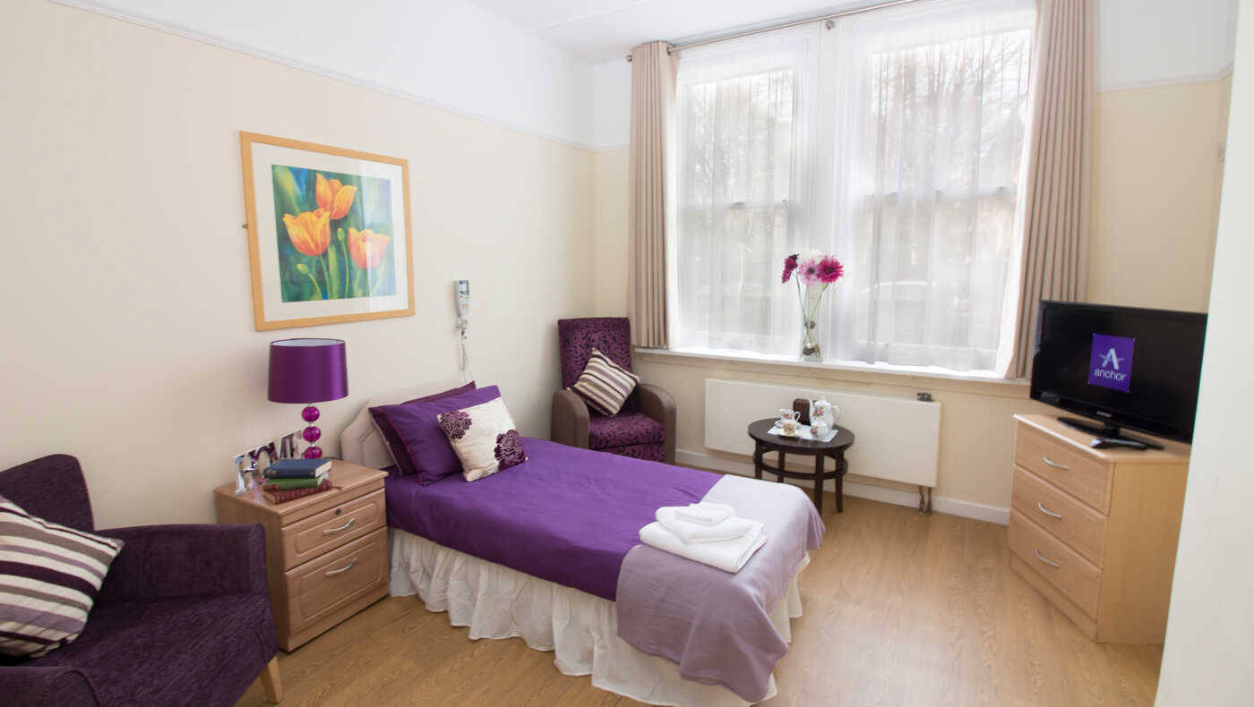 A cozy resident room with a purple theme and natural light