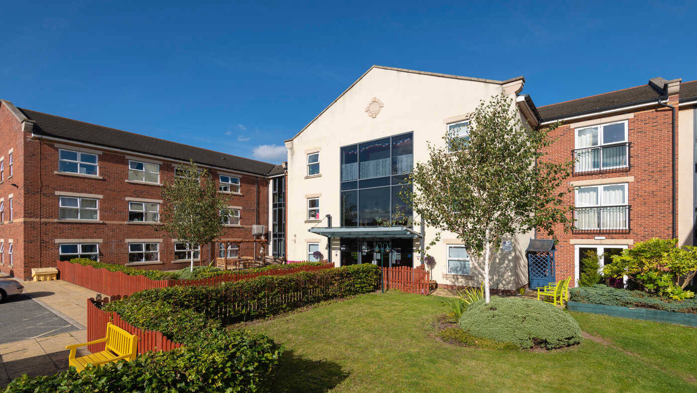 Exterior view of a senior living facility with gardens and seating
