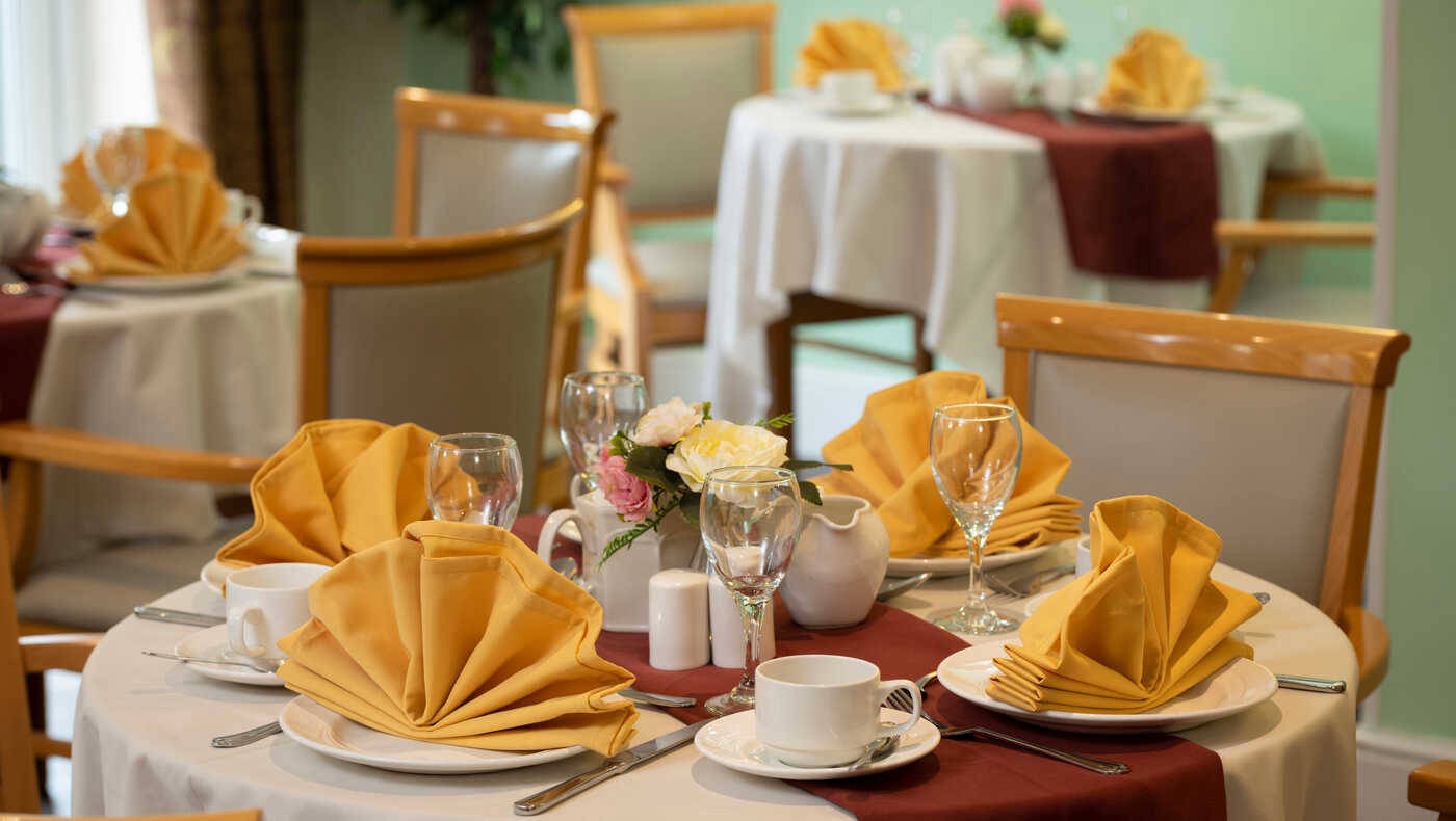 Elegant dining setup with yellow napkins and flower centerpiece