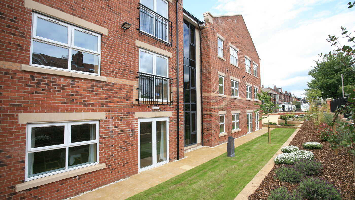 Exterior view of a brick building with gardens