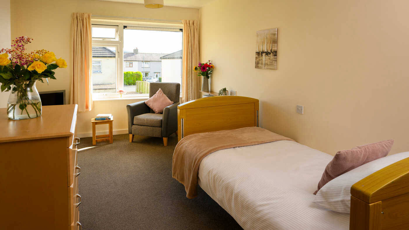 Cozy interior of a resident's room with a bed and seating.