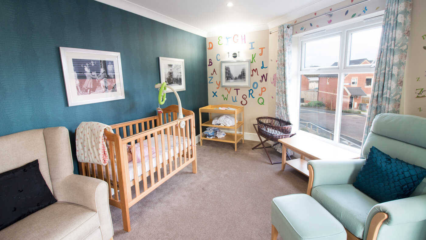 Bright resident room with a crib and seating area