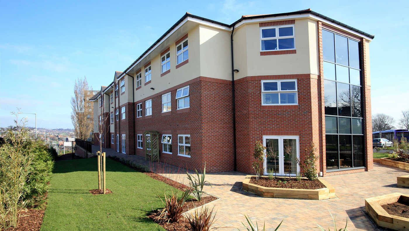 Exterior view of a senior living facility with landscaped garden