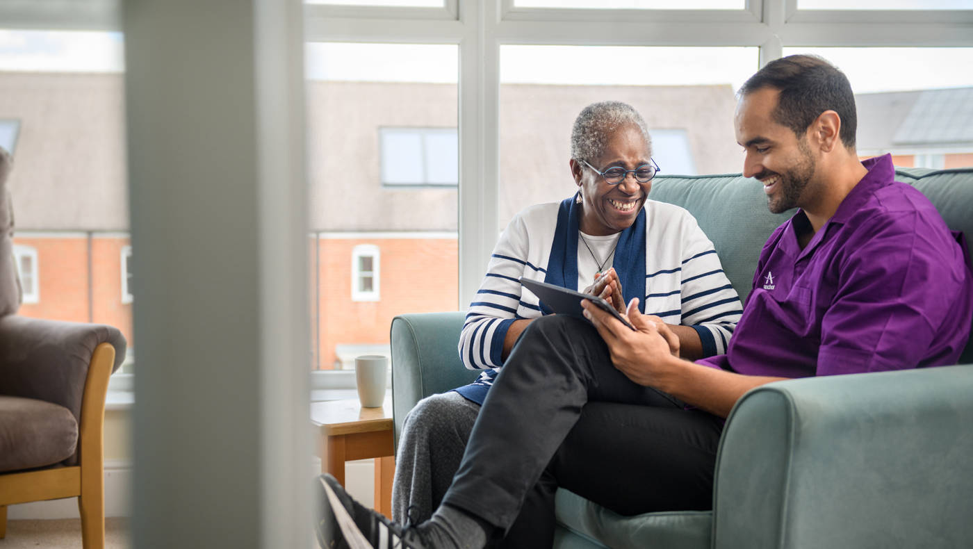 Staff member and resident smiling while using a tablet