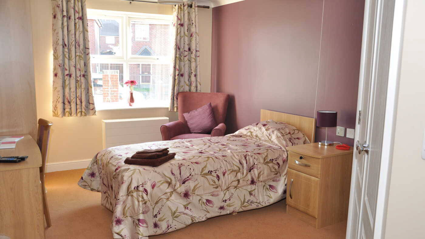 Cozy resident room with floral bedding and natural light