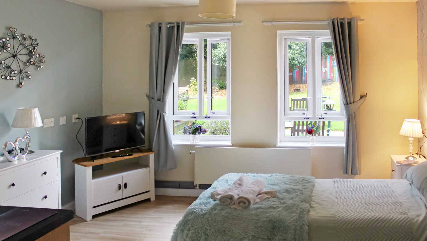 Well-furnished resident room with windows overlooking a garden