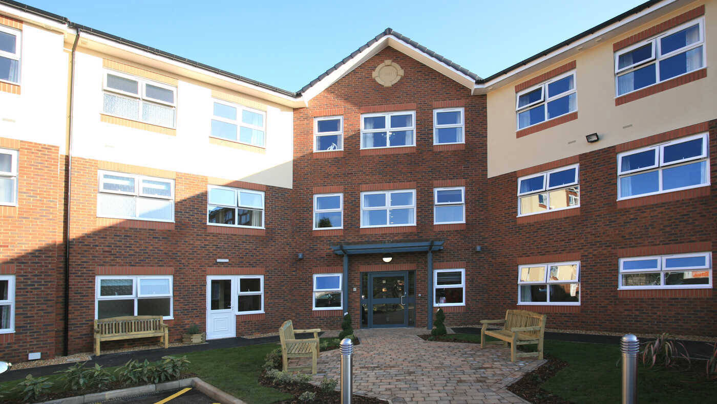 Exterior view of a senior living facility with benches