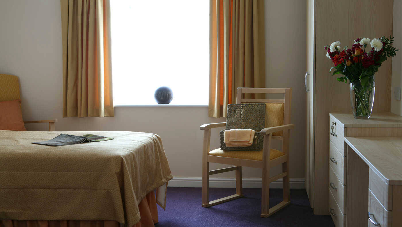 Cozy interior of a resident room with a bed and chair