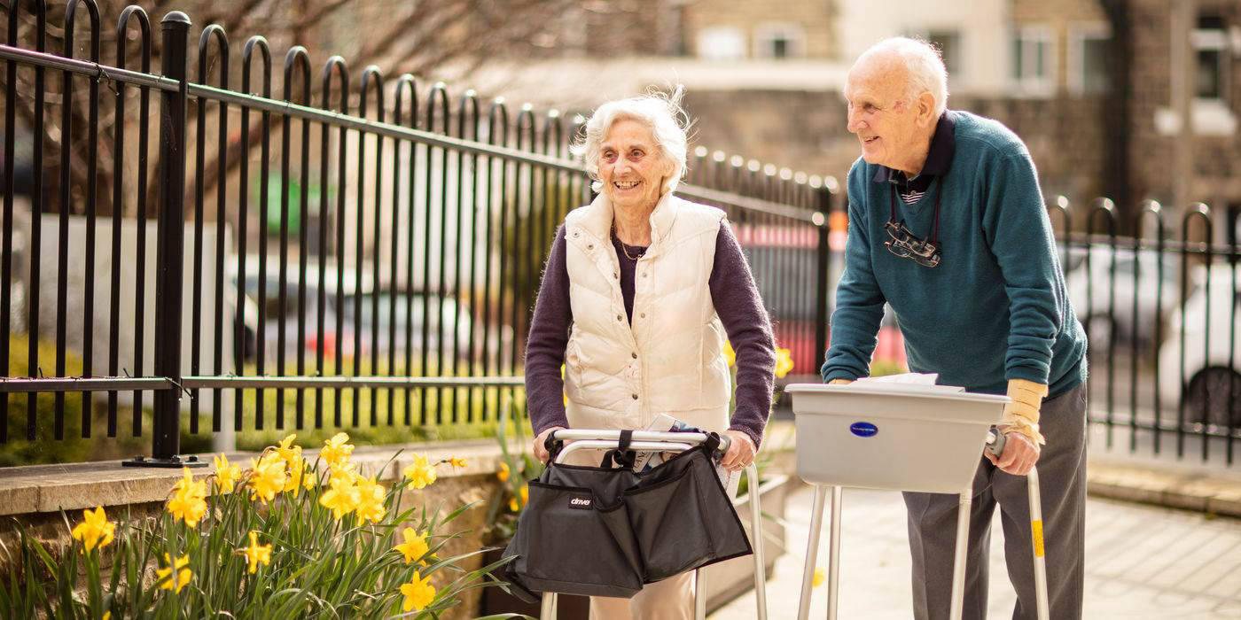 Two residents enjoying a walk outdoors near flowers