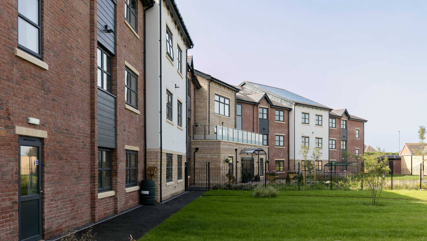 Exterior view of a senior living facility with garden