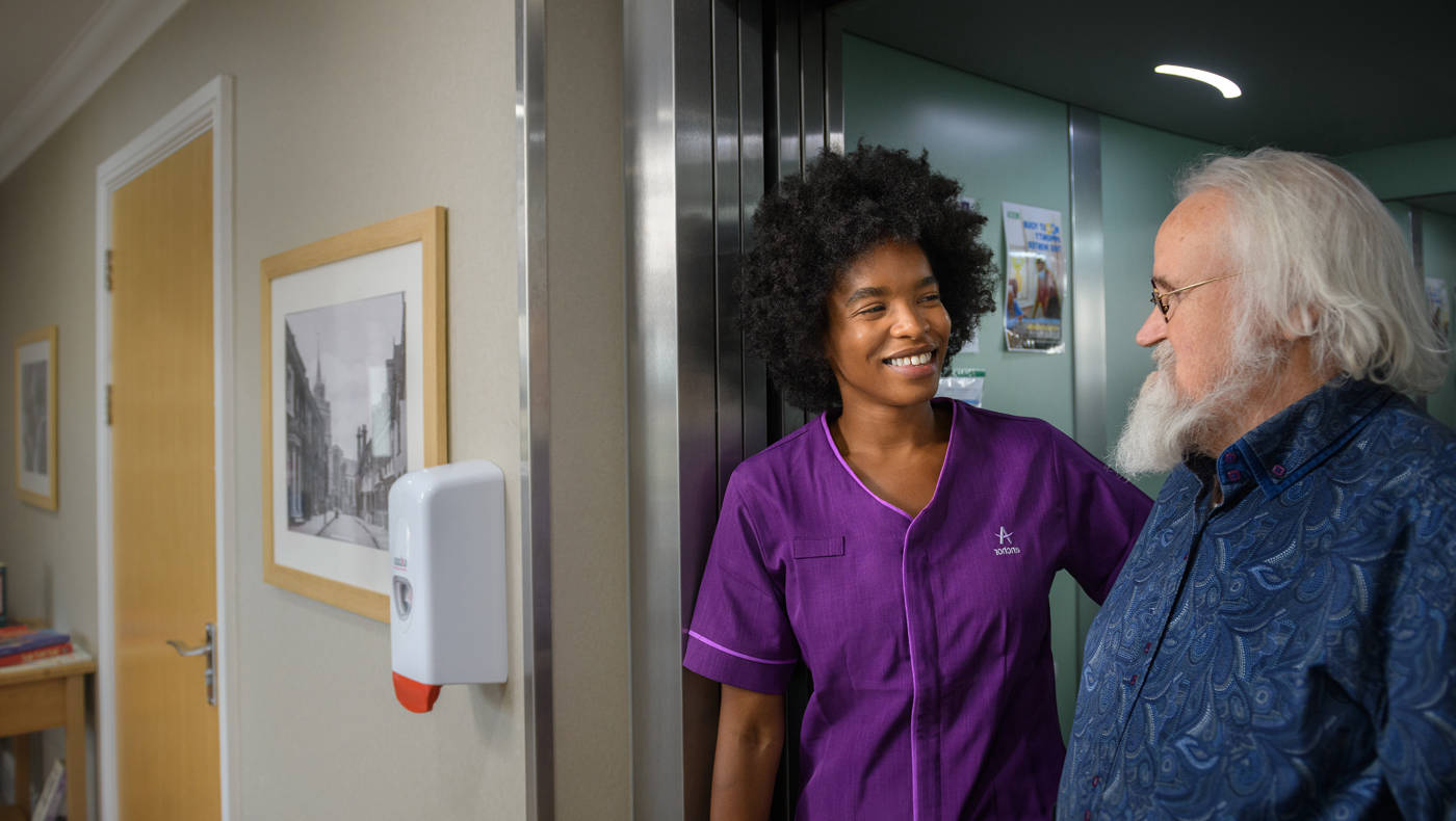 A caregiver interacting with a resident in a hallway