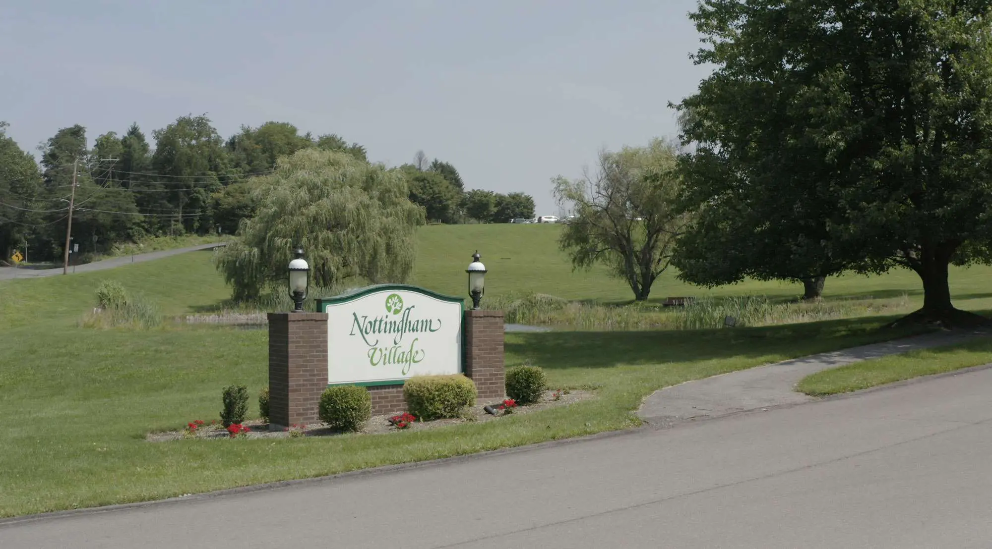 Signage for Nottingham Village near a green landscape