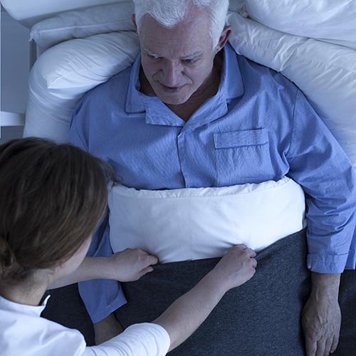 Caregiver assisting a senior in bed