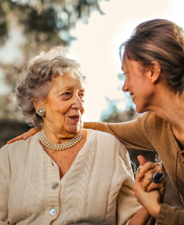 Elderly woman enjoying time with caregiver outdoors.