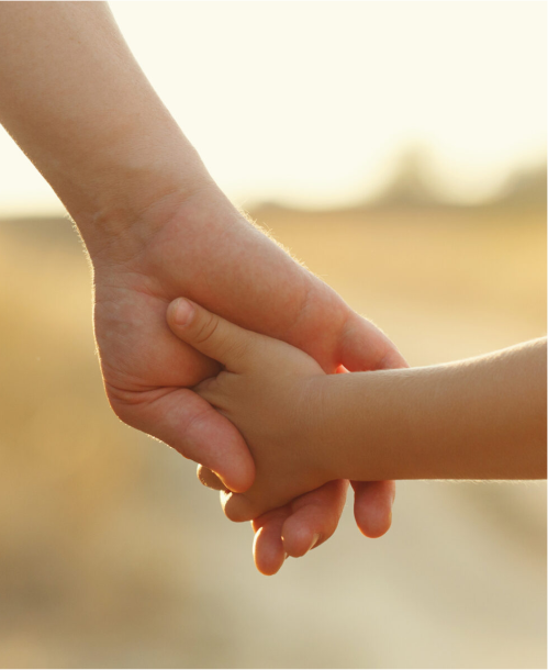 Two hands holding in a warm, outdoor setting