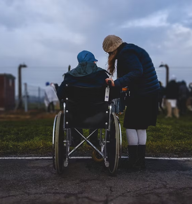 Resident in a wheelchair outdoors with caregiver.