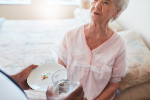 Senior woman receiving medication from caregiver