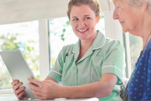 Nurse smiling while using a tablet with a resident.