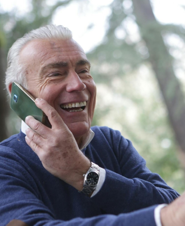 Senior man smiling while talking on the phone outdoors.