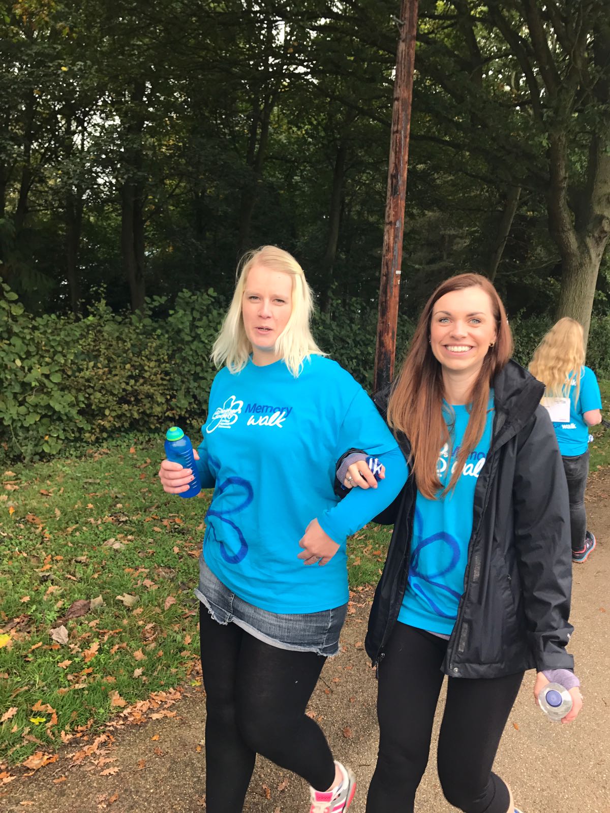 Two women walking outdoors in matching blue shirts.