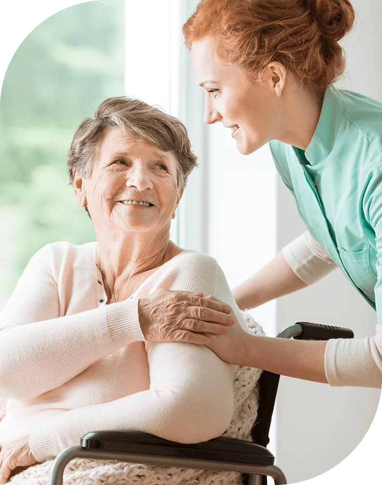 Caregiver assisting a happy resident in a bright room.