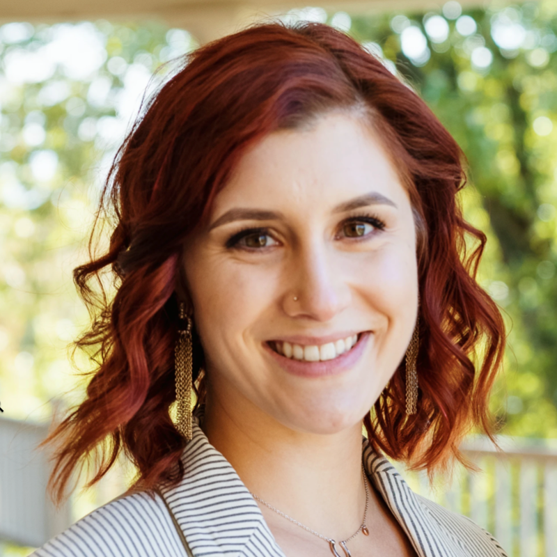A smiling staff member in a garden setting.