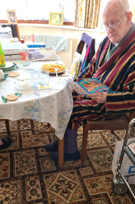 Elderly man reading while having a meal.