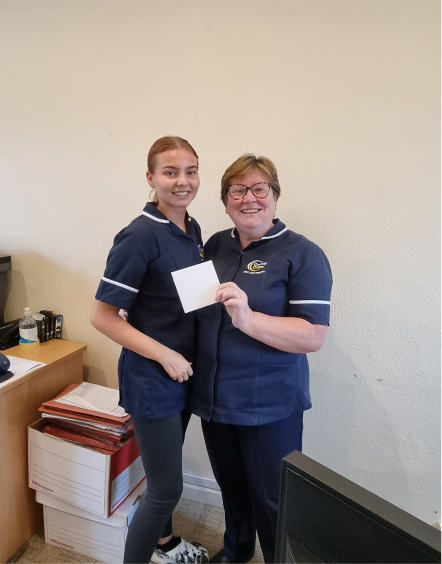 Two staff members holding a card inside the facility.