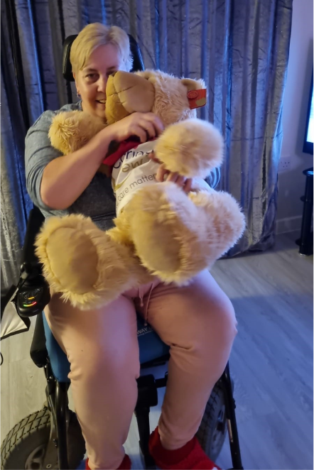 Resident with a teddy bear in a wheelchair.