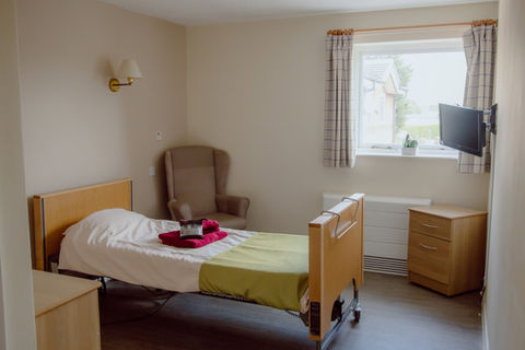 A private resident room with a bed and chair
