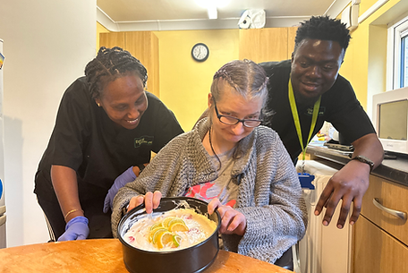 Staff assisting a resident with cake preparation.