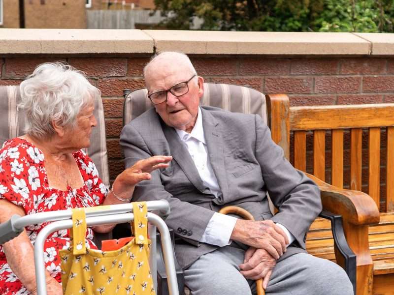 Two residents engaged in conversation outdoors.