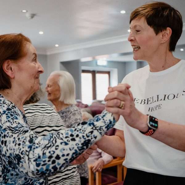 Residents and staff engaging in a dance together.