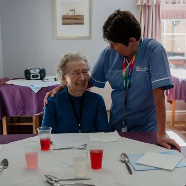 Staff member interacting with resident in a dining area.